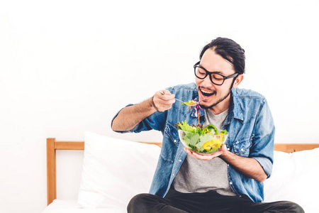 年轻人吃有机健康沙拉与蔬菜在碗在家庭床上. 饮食食品与健康生活理念