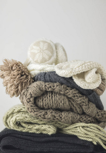 暖羊毛针织冬秋季的衣服, 叠成一堆在一张白纸上。毛衣, 围巾, 手套, 帽子, 耳机。文本的位置。Copyspace