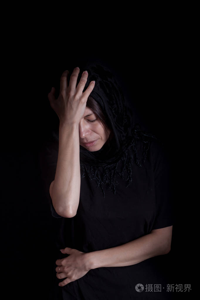 戴黑色头巾的漂亮女人沮丧(黑色背景)