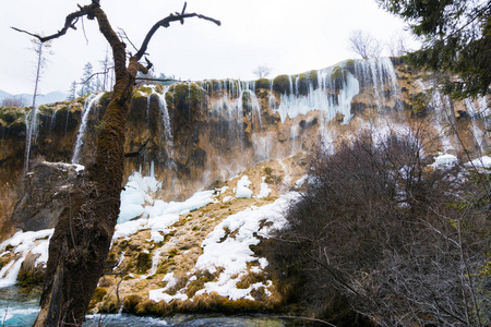 瀑布在森林里。岩石上的水流。在针叶林上清洁冷水。石头在雪地里。强大的岩石和水流