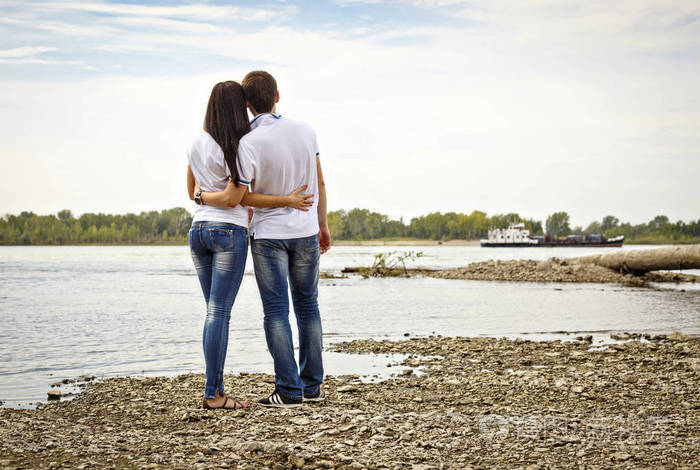 年轻夫妇牵着对方的手从岸上的河边, 爱情故事