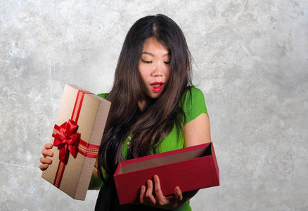孤立的灰色背景肖像年轻快乐和美丽的亚洲中国妇女举行礼物盒收到生日或圣诞礼物打开包裹兴奋和惊讶