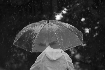 一位妇女抱着一把雨伞走在街上