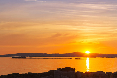 Arousa 河口在金色日落与沿海岩石在前景上