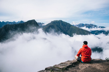 高假日穿着积极穿着的年轻人的背部观看坐在莲花在山顶享受惊险的风景