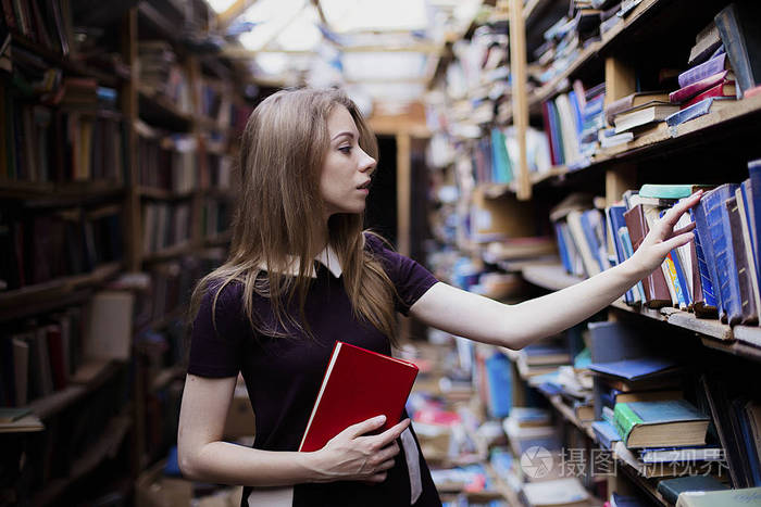 生活方式的一个可爱的学生女孩在老式图书馆或书店的肖像