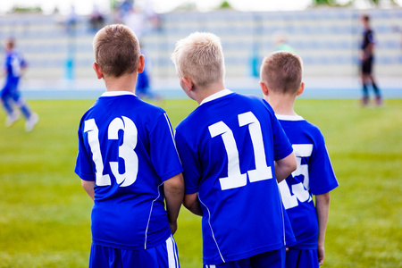 年轻的足球队。储备球员站在一起，看着青年队足球赛足球锦标赛。体育背景