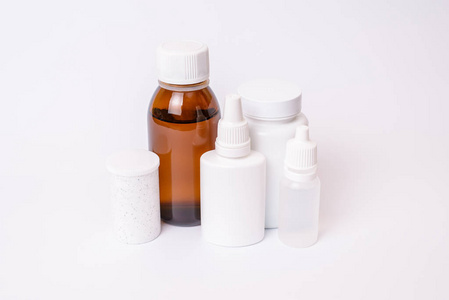 空白补药治疗模式头痛药物食品补充片概念。关闭白色瓶子的照片与丸耳眼药水透明棕色瓶隔离在白色背景上