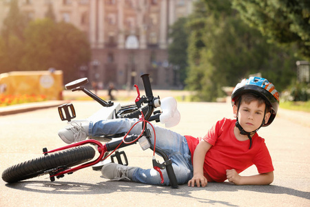 逗人喜爱的小男孩从他的自行车跌倒了室外照片