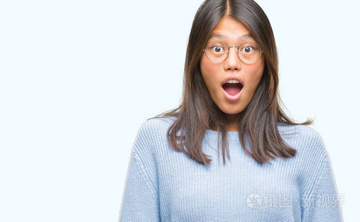 年轻的亚洲妇女穿着冬季毛衣在孤立的背景下害怕和震惊与惊喜的表情