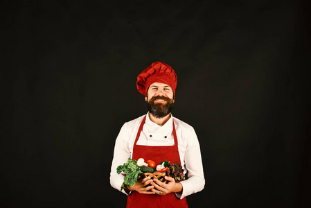 厨师拥有生菜,西红柿,胡椒和蘑菇.黑暗背景的胡子男人照片