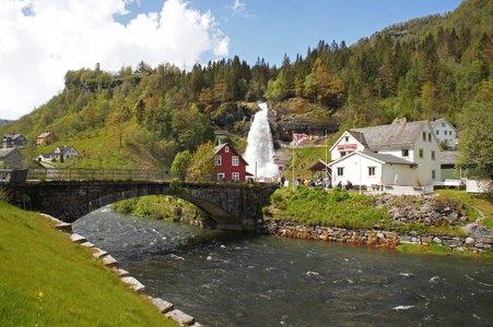 Steinsdalsfossen 瀑布中半胱氨酸在河景观与叶栅环绕山和传统的挪威，斯堪的纳维亚的房子