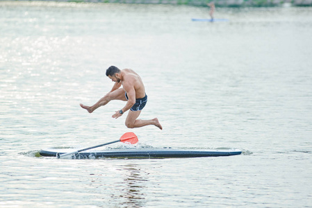 在湖泊水中跳跃的运动员从支撑板