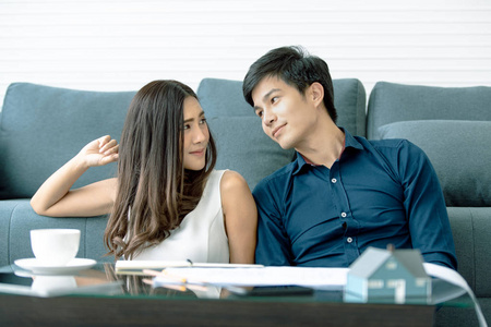 亚洲青少年夫妇在餐桌上的目光接触微笑正在计划与他的妻子在现代公寓