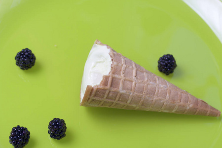 在华夫饼角吃冰淇淋。躺在白色的背景上。附近躺着几浆果的黑莓