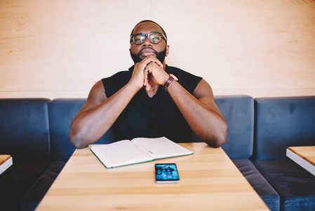专注于商务策略坐在桌子上的笔记本, 沉思的非洲裔美国人时髦的家伙