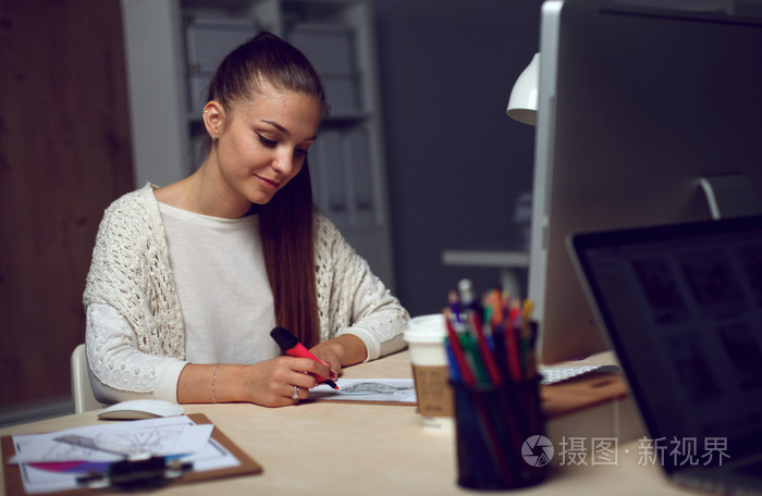 在办公室里,坐在办公桌前工作的年轻女子照片