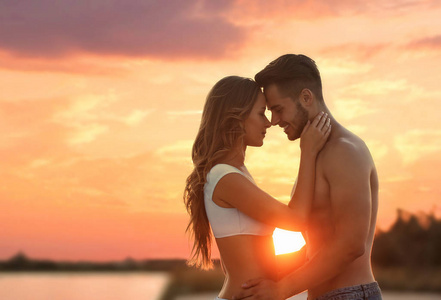 快乐的年轻夫妇在海滩户外日落