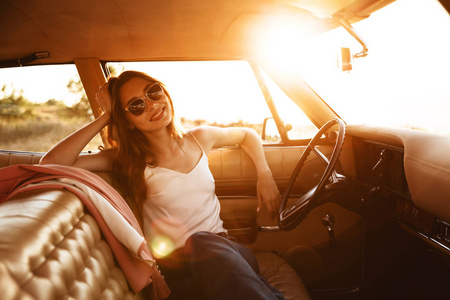 快乐美丽的女人坐在汽车里的太阳镜