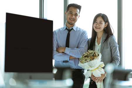 亚洲商人和女商人在现代办公室调情, 手里拿着鲜花, 商业中的爱情观念
