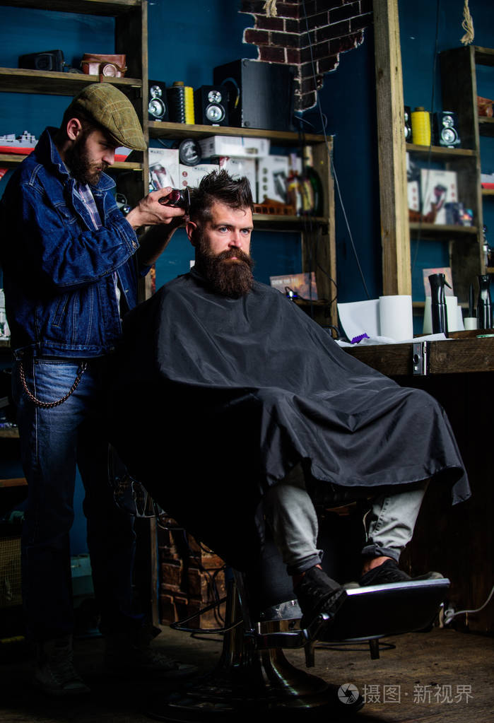 理发师与剪刀修剪头发在客户的颈背。时髦的客户得到理发。理发师理发剪头发胡子的家伙理发店背景。时髦发型概念