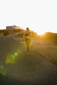 夕阳中的太阳升起的女人沿着一条路奔跑