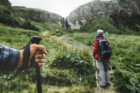 徒步旅行者在山区，登山杖旅行人特写手中。旅行的生活方式度假概念