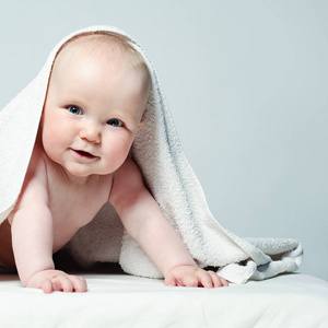 性格开朗的宝贝，用白毛巾。快乐的小女孩，6 个月大