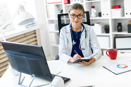 主任医师一个穿着白色长袍的年轻女孩坐在办公室的桌子旁, 手里拿着