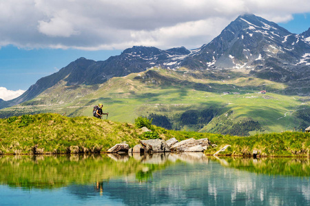 女性旅行者与背包徒步登山小径旁边的山湖和欣赏瑞士阿尔卑斯山在 Bagnes 地区, 瑞士的看法