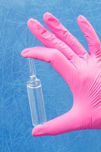 女医生在详细安瓿和医学的粉红色手套的手