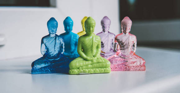 多彩多姿的塑料佛像在一个轻的背景。世界上的现代宗教