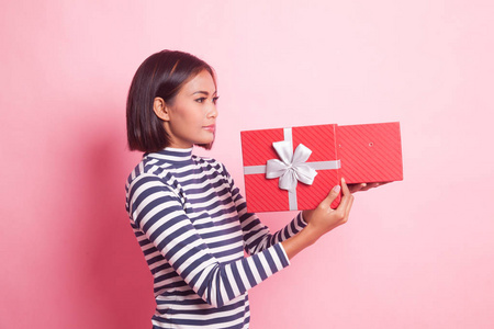 年轻的亚洲妇女打开一个礼品盒粉红色背景