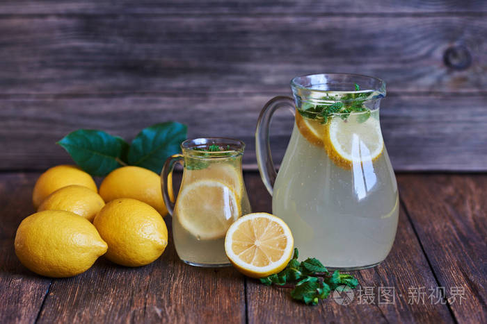 自制柠檬水与薄荷和冰, 新鲜的柠檬在木质背景。健康和排毒夏日饮品