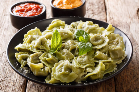 美味的菠菜绿色 cappelletti, 馄饨, 饺子与帕尔马干酪, 罗勒, 酱汁特写在桌子上。horizonta