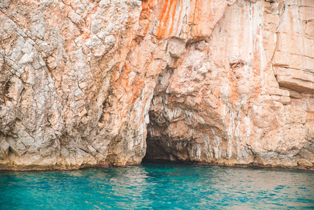 以蔚蓝的水在岩石峭壁上的洞穴景观。暑假概念