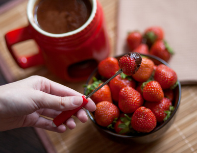 甜点。在木制的背景上的成熟，明亮草莓红杯巧克力火锅