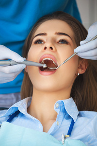 年轻的女人得到她的牙齿由牙医检查