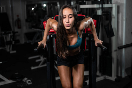 健身妇女在 crossfit 体育馆的不均匀酒吧做俯卧撑。锻炼生活方式概念