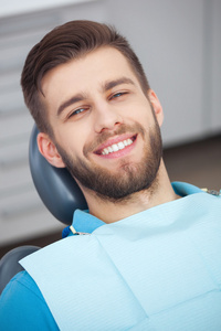 快乐患者坐在牙医的椅子上的肖像