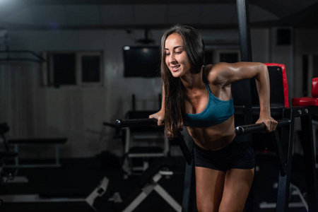 健身妇女在 crossfit 体育馆的不均匀酒吧做俯卧撑。锻炼生活方式概念