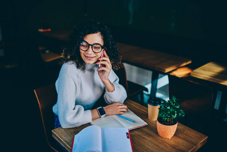 技术和沟通的概念, 微笑成功的时髦的女孩穿着时髦的眼镜坐在咖啡店与文学研究使用手机进行交谈
