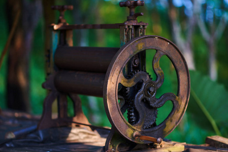 废弃的棕榈油出版社。绿色景观中压榨棕榈油的旧铁压机