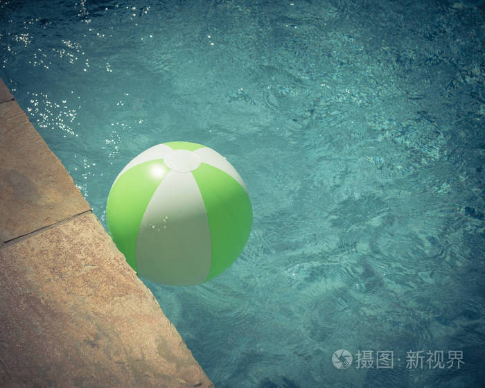 特写顶部景观一个明亮的绿色沙滩球附近游泳池的应对优势。漂浮在清爽的蓝色水中, 波浪反射在夏季太阳附近的泳池甲板和瓷砖。孩子的救命