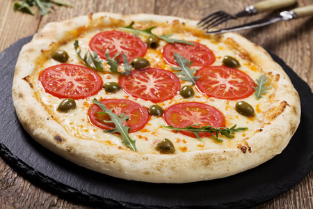 比萨素食者在板材在石头黑尝试用新鲜的蕃茄和橄榄