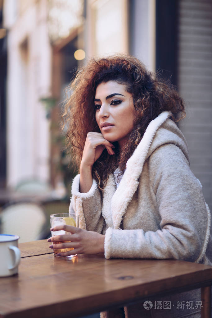 年轻的阿拉伯妇女坐在街道上的城市酒吧.