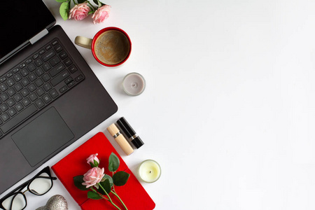 妇女的工作场所与笔记本电脑键盘, 蜡烛, 眼镜, 笔记本, 咖啡, 口红和玫瑰在白色的背景。美容时尚博客的概念。顶部视图