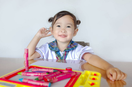快乐可爱的亚洲小朋友坐在桌边玩五颜六色的玩具