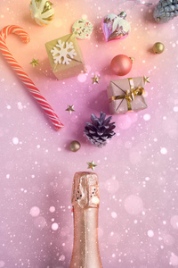香槟瓶与不同的圣诞装饰粉红色的背景。新年理念。平躺