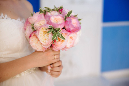 一个被裁剪的婚礼框架的特写是新娘手中的一束玫瑰花。穿着婚纱的女孩拿着花